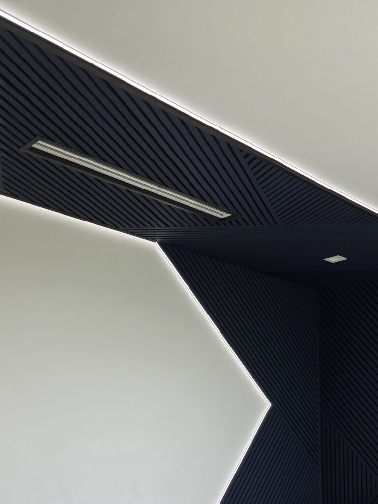 Navy wood slat accent wall with LED lighting wrapping onto the ceiling