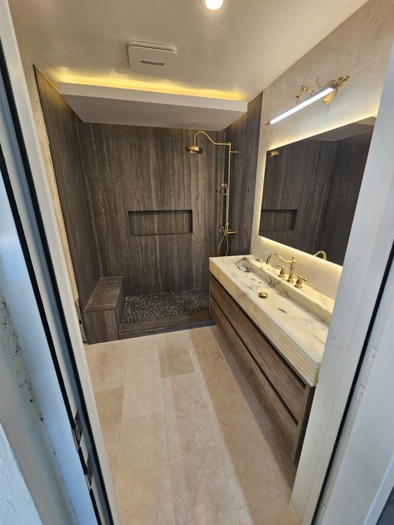 Bathroom with a backlit mirror, LED cove lighting and a long floating vanity
