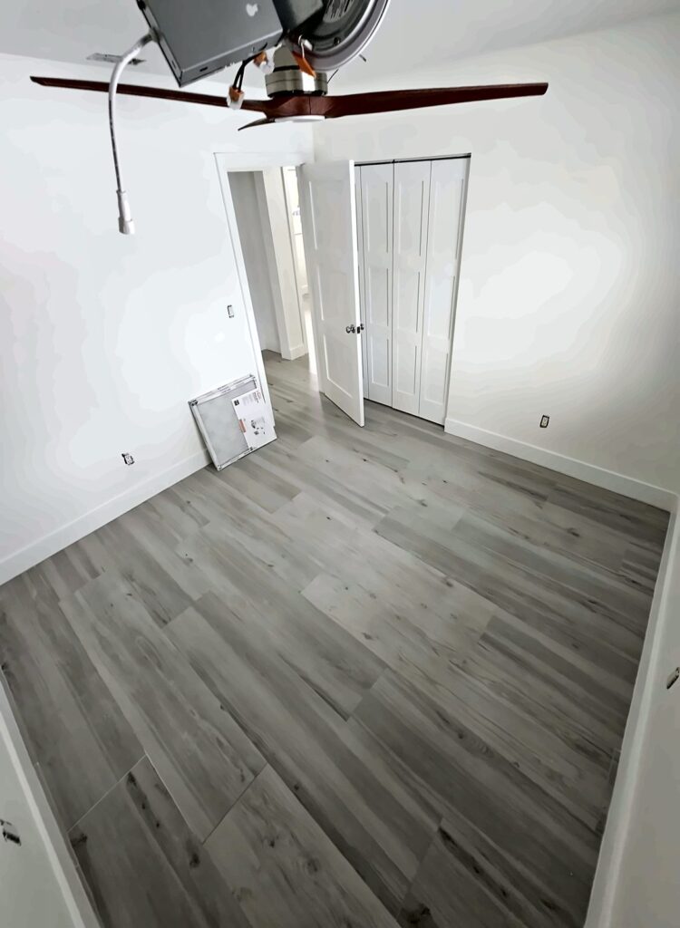 Empty bedroom with new gray vinyl plank flooring and fresh paint
