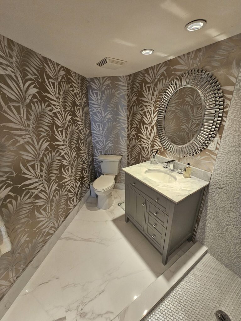 Bathroom with botanical wallpaper, a round mirror and a gray vanity
