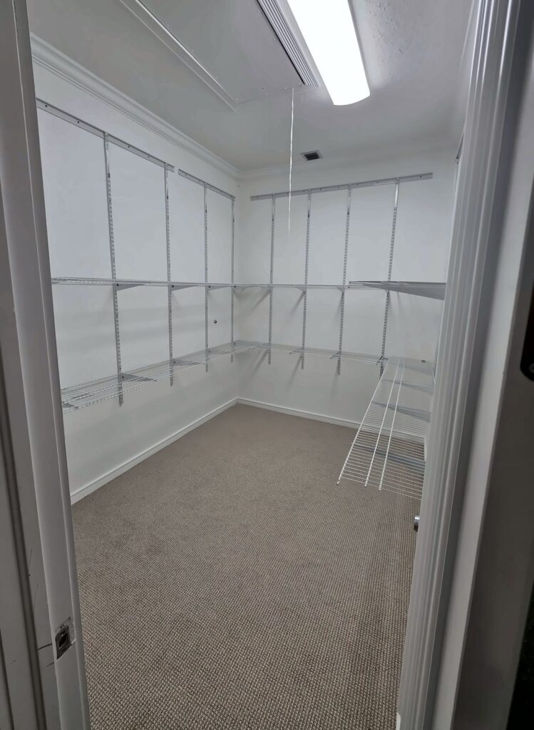 Walk-in closet with new white wall-to-wall shelving