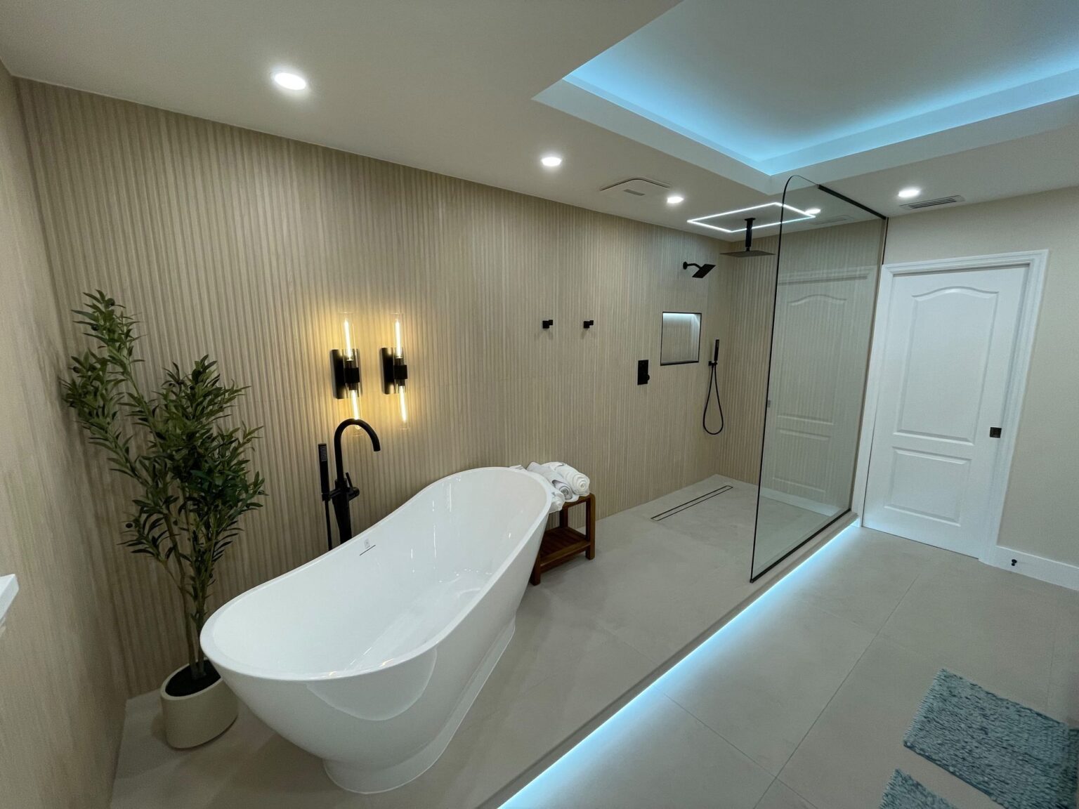 Master bathroom with a freestanding tub, fluted wall panels, sconces and LED cove lighting