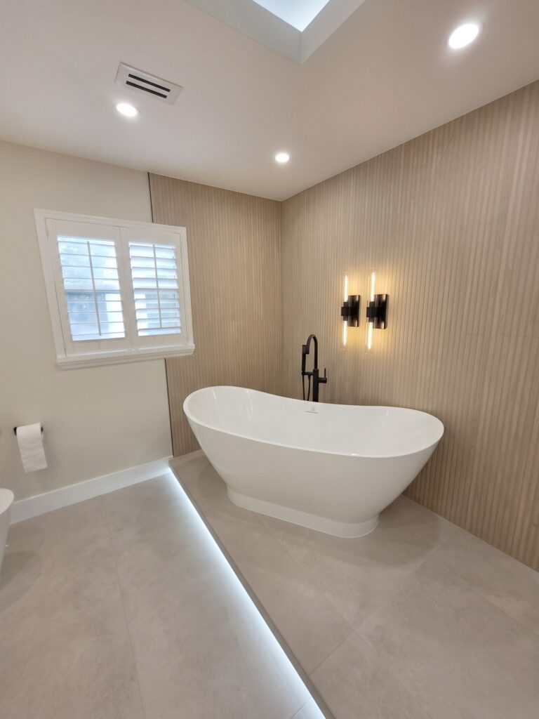 Freestanding tub under plantation shutters with black wall sconces