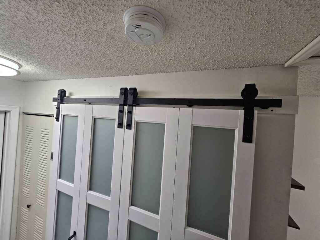 White closet barn doors with frosted glass panels on a black sliding track