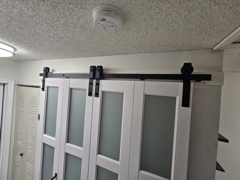 White closet barn doors with frosted glass panels on a black sliding track