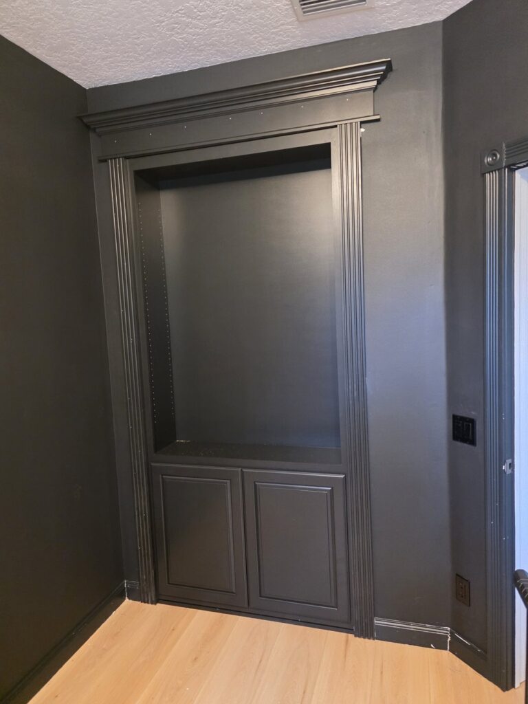 Dark painted wall with a hidden door and crown molding