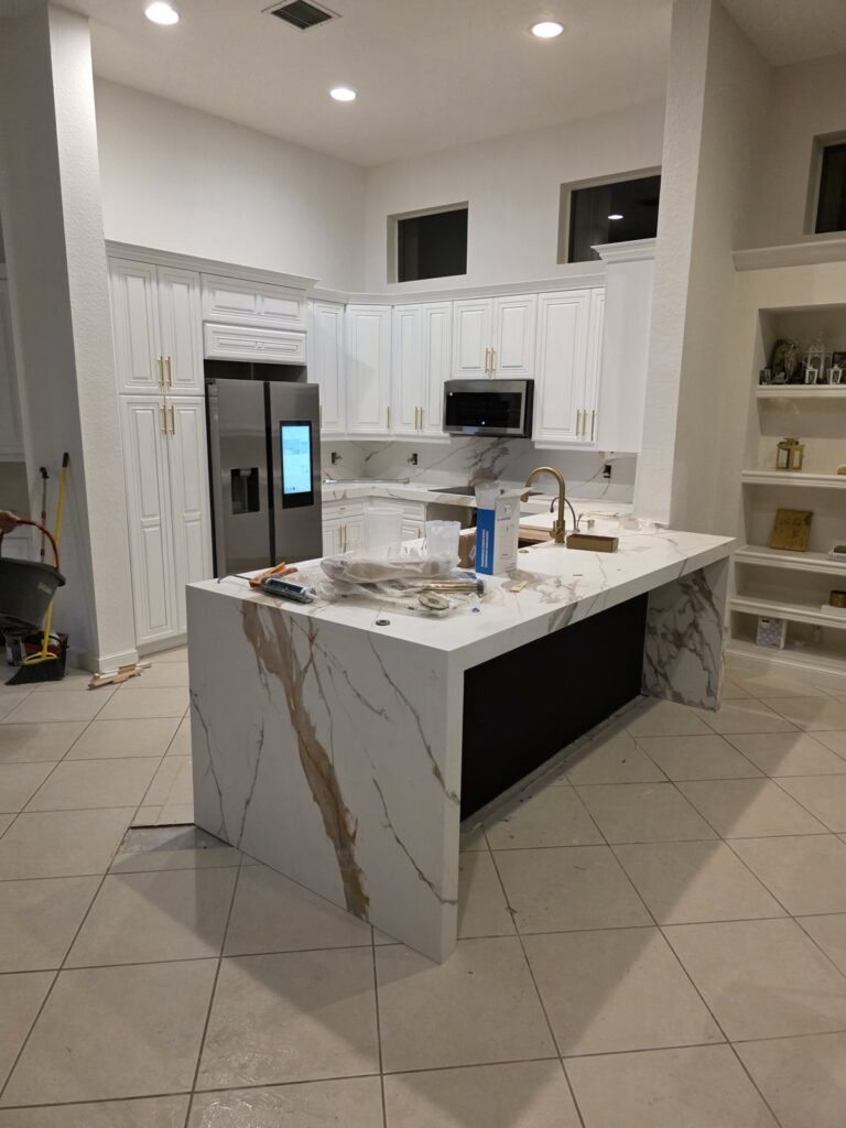Kitchen with a marble waterfall island and white cabinets