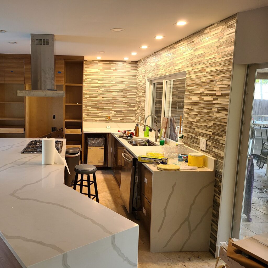 Kitchen with a waterfall quartz island, stacked-stone feature wall and walnut cabinets