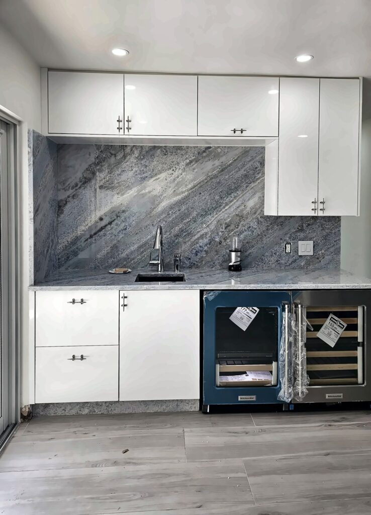 White kitchen cabinets with a full marble-look backsplash and wine fridge