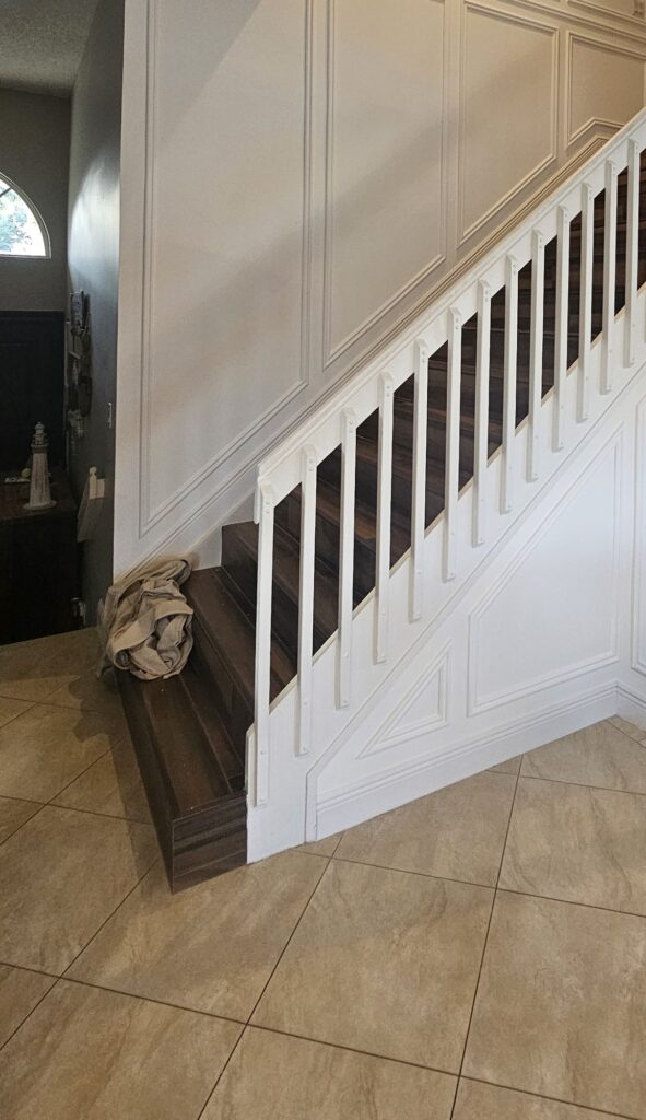 Same staircase wall after full-height white picture-frame paneling