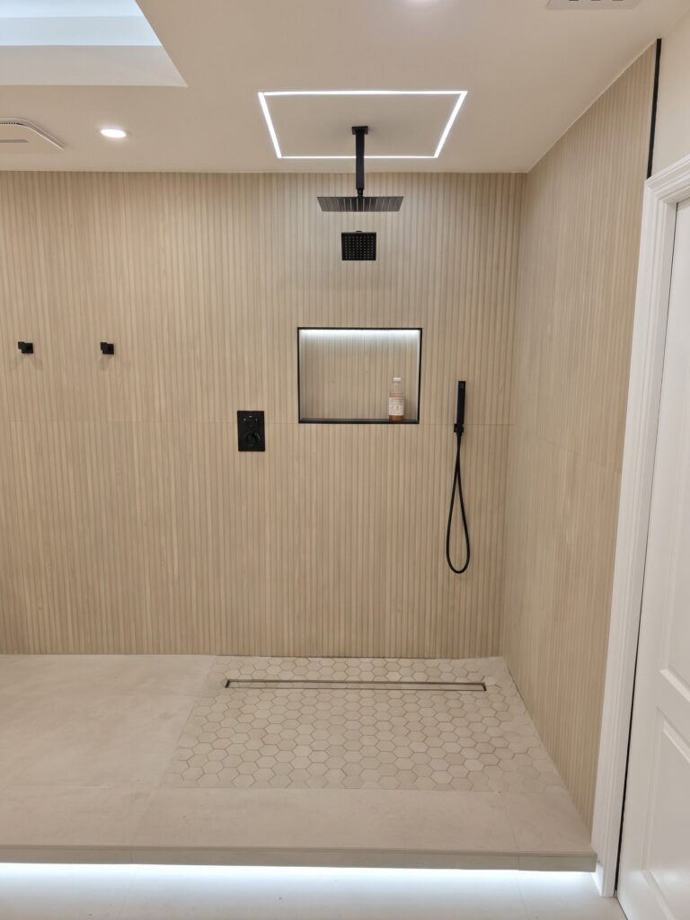 Finished walk-in shower with wood-look slat walls, rain head, niche and linear drain