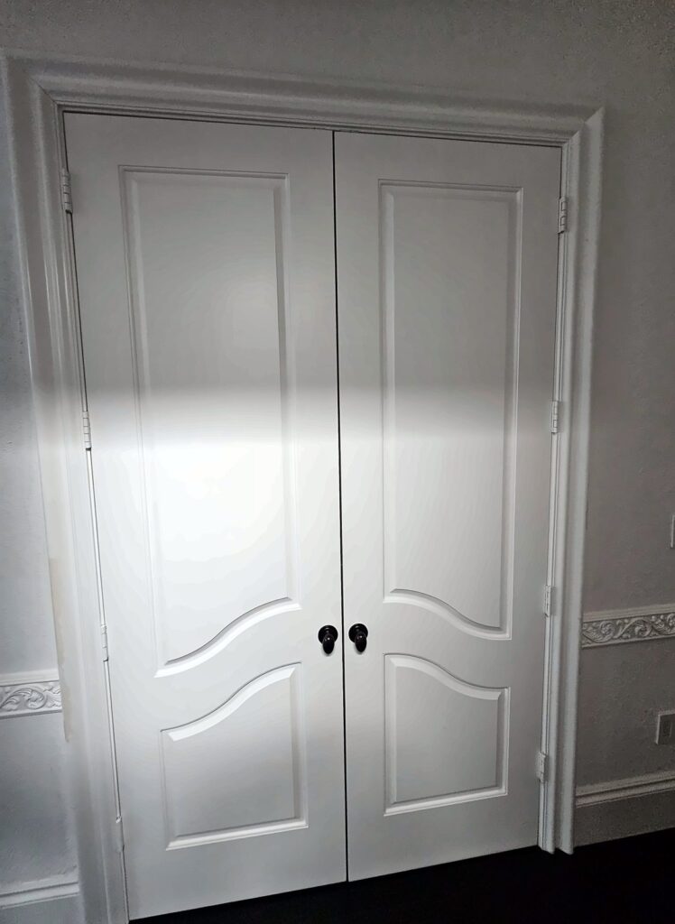 New white double closet doors with black knobs