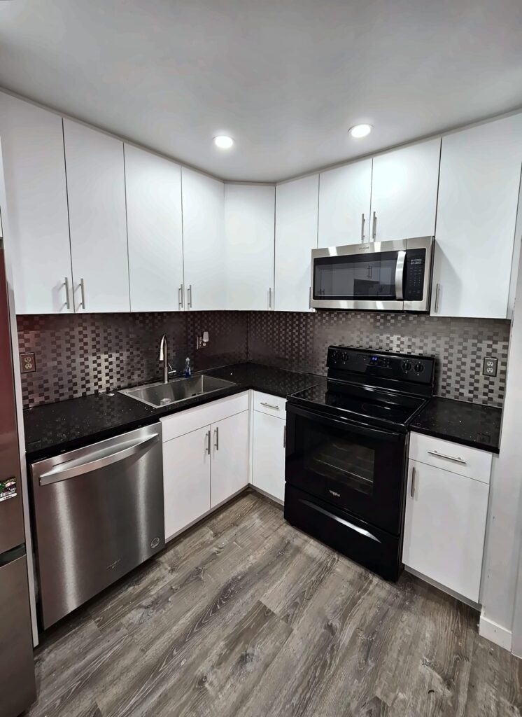 White kitchen with dark counters and a mosaic backsplash
