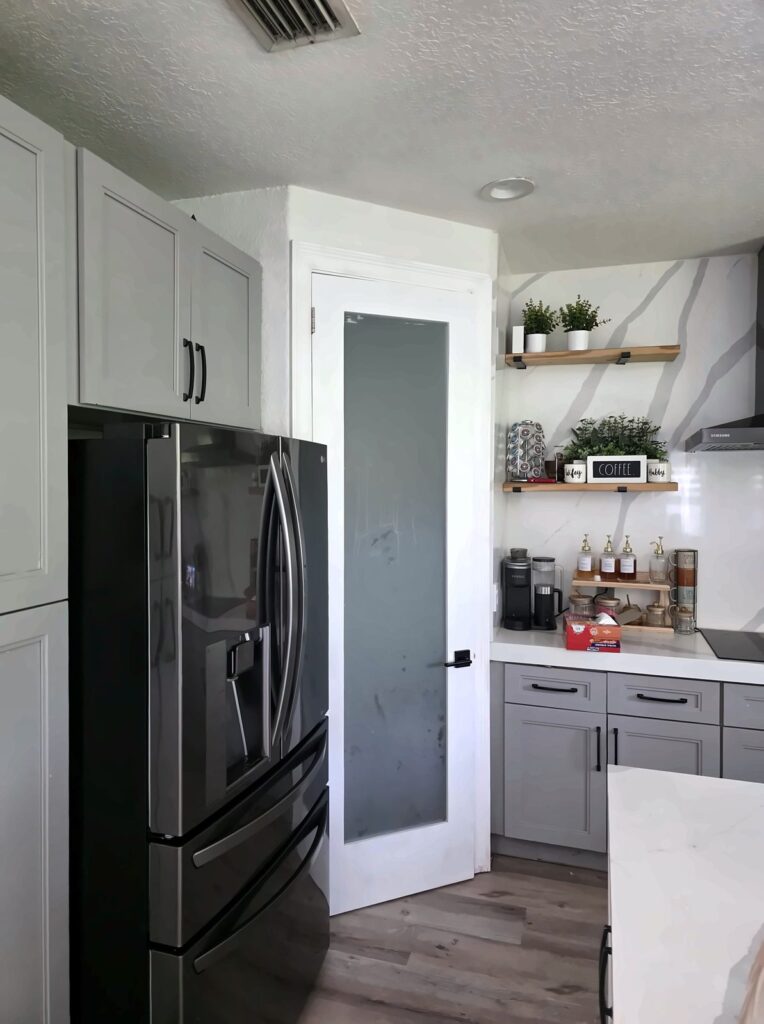 White shaker kitchen with open shelves and a frosted pantry door