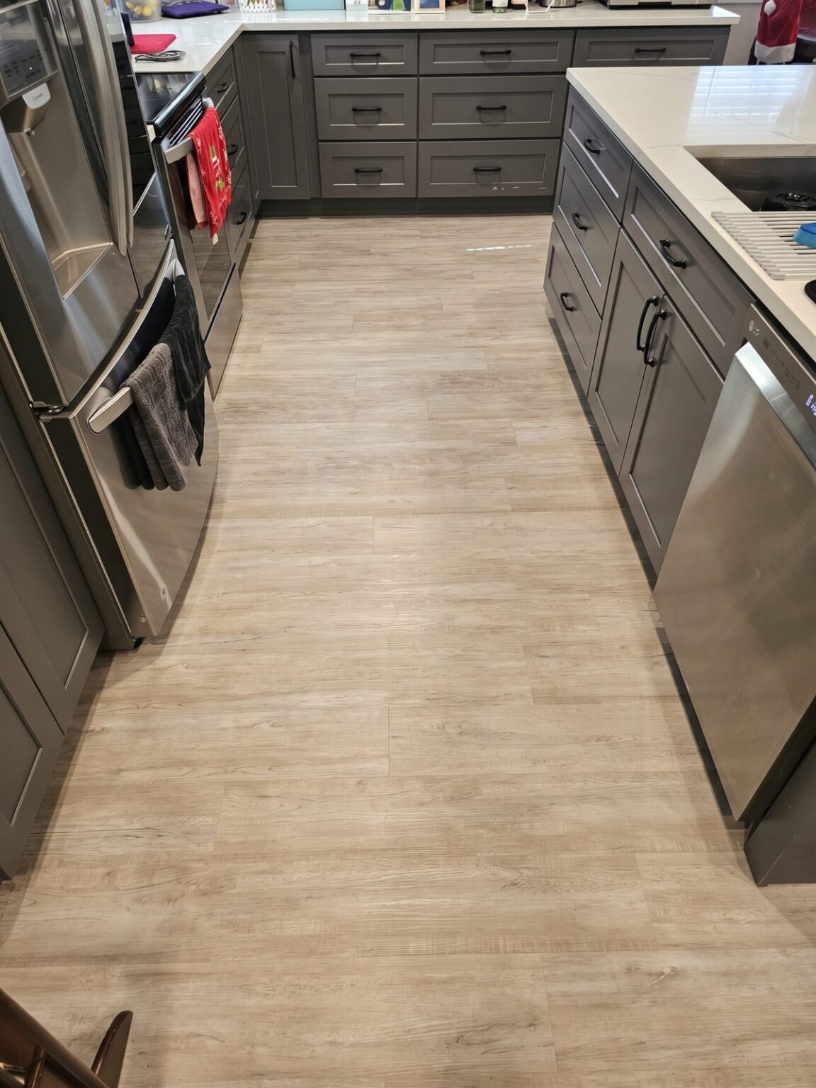 Finished wood-look tile floor running through a gray kitchen