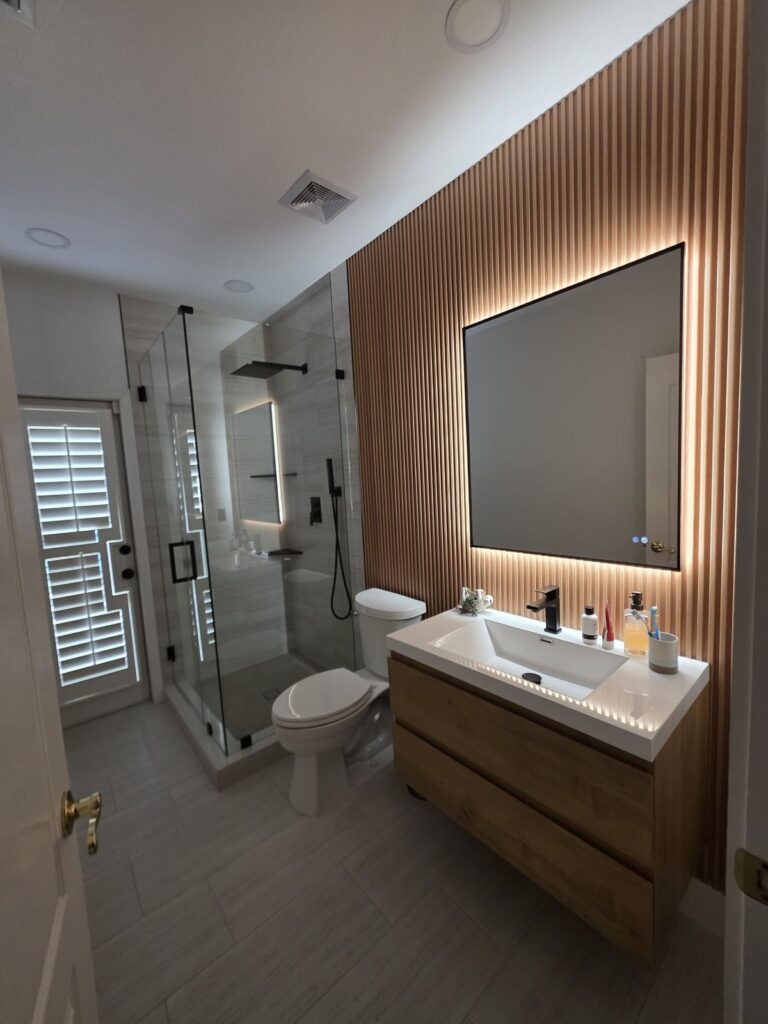 Bathroom with a vertical wood slat accent wall and backlit mirror